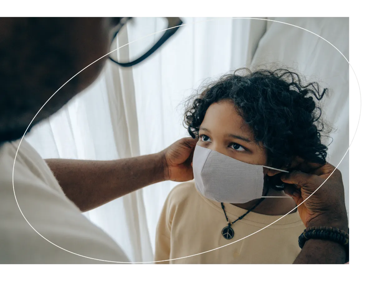 An adult helps a child put on a face mask